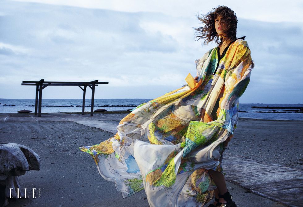 一個女人穿著印花洋裝站在沙灘上