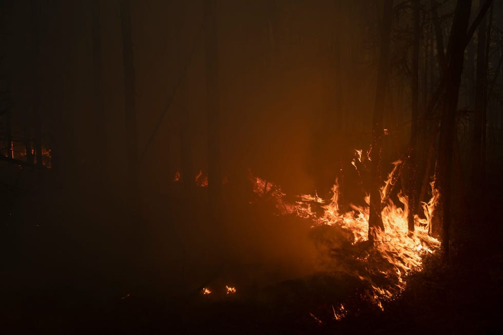 Terwijl een bosbrand het dorp Kjoejoreljach in Jakoeti nadert drijven dichte rookwolken over het dorp en een snelweg
