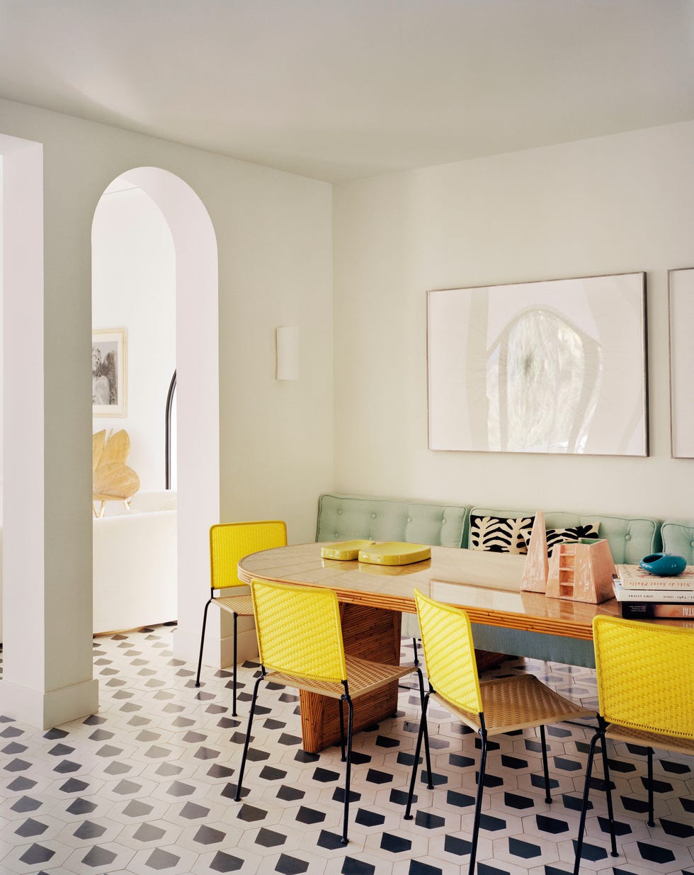 dining area with black and white tiles and yellow chairs by india mahdavi