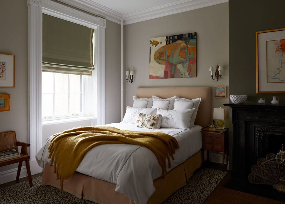 bedroom in whites and caramel tones with artwork over the bed and matching scones on either side