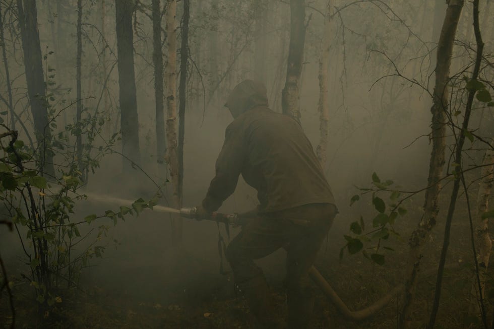 Kim Konstantinov 36 lid van de plaatselijke vrijwillige brandweer bestrijdt een natuurbrand in de buurt van het dorp Kjoejoreljach