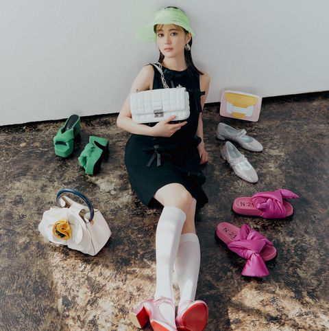 a person sitting on the floor with a pile of shoes and a sign