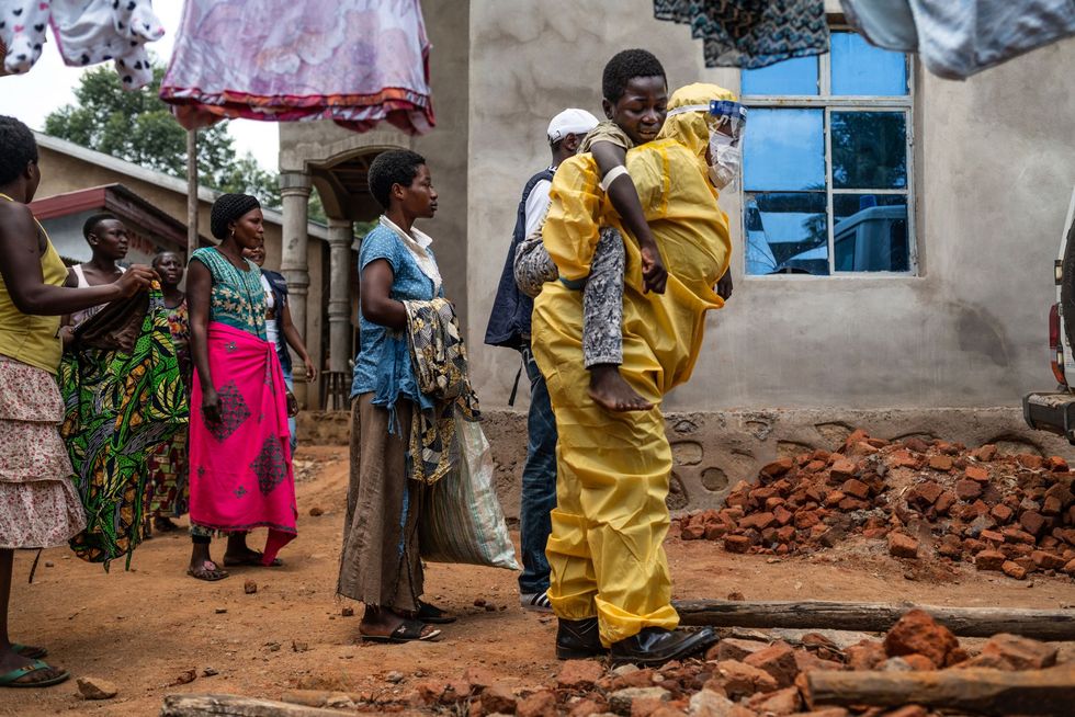 Een zorgmedewerker draagt de 14jarige Kakule Kavendivwa naar een gereedstaande ambulance in Beni De dag ervr hadden Kakules zussen hem naar de dichtstbijzijnde kliniek gebracht maar vluchtten weer toen het team hen probeerde te overreden de jongen naar een Ebolacentrum te brengen Het Ebolacentrum waarschuwde de WHO die de familie opspoorde Na urenlange gesprekken met WHOmedewerkers van de plaatselijke gemeenschap liet de familie toe dat de jongen ter behandeling door een ambulance werd meegenomen