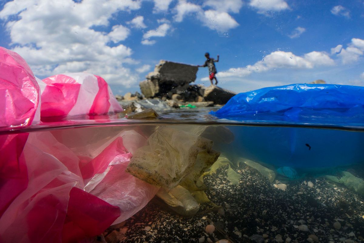 Kinderen spelen op de met plastic vervuilde oever van de Baai van Manilla op de Filipijnen