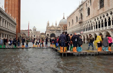 Mensen lopen op 29 oktober 2018 via loopplanken over het ondergelopen San Marcoplein tijdens de jaarlijkse hoogwaterperiode in Veneti