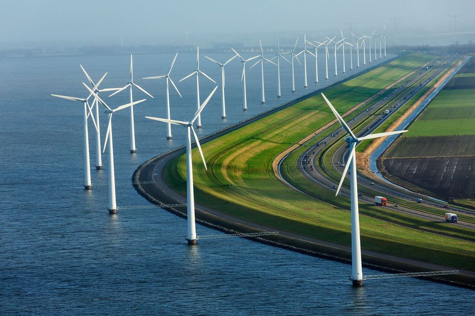 Geflankeerd door windmolens beschermt deze dijk in Flevoland Nederland akkers die vrijwel geheel onder zeeniveau liggen