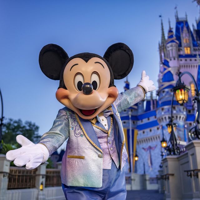 mickey mouse standing in front of cinderella castle at magic kingdom park with 50th anniversary decorations