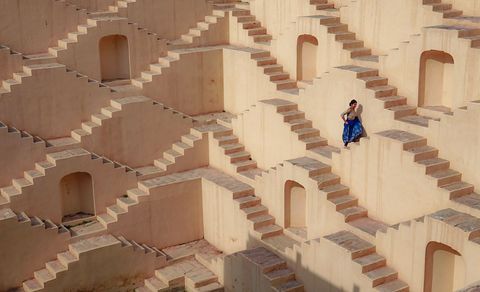 De diepblauwe rok van een vrouw valt op tegen de achtergrond van de Escherachtige trappen van Panna Meena ka Kund in JaipurIndia In het trappencomplex uit de zestiende eeuw werden volksbijeenkomsten gehouden