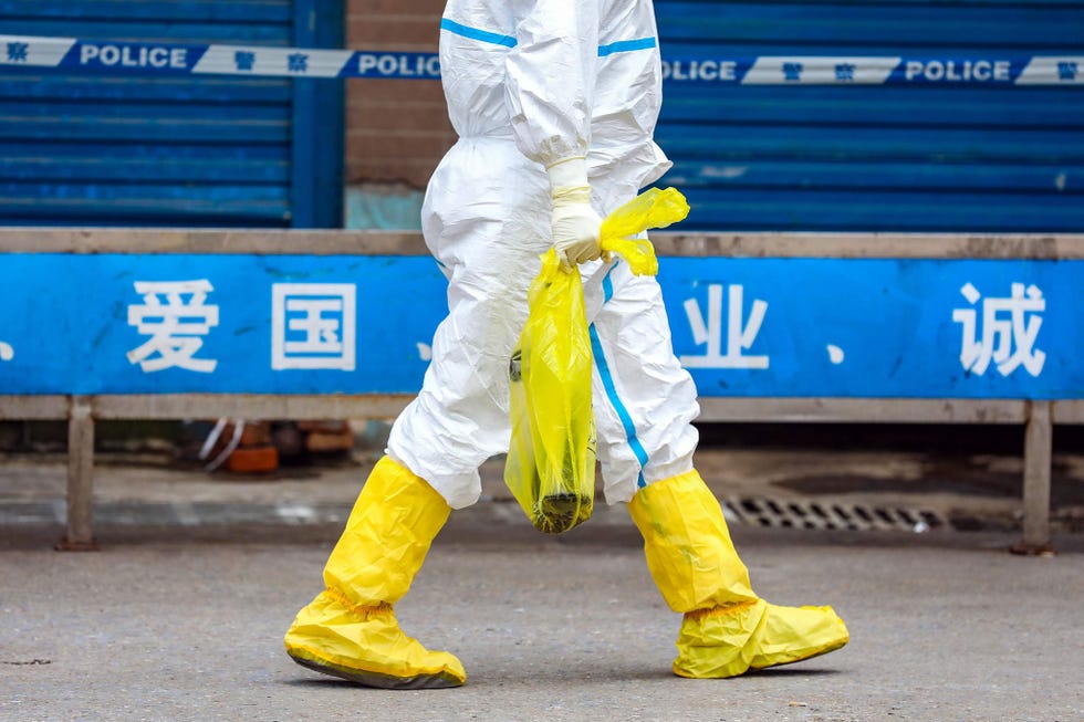 Op de markt voor wilde dieren in Wuhan waar het coronavirus in december 2019 uitbrak draagt een medewerker een levende salamander weg nadat de markt werd gesloten
