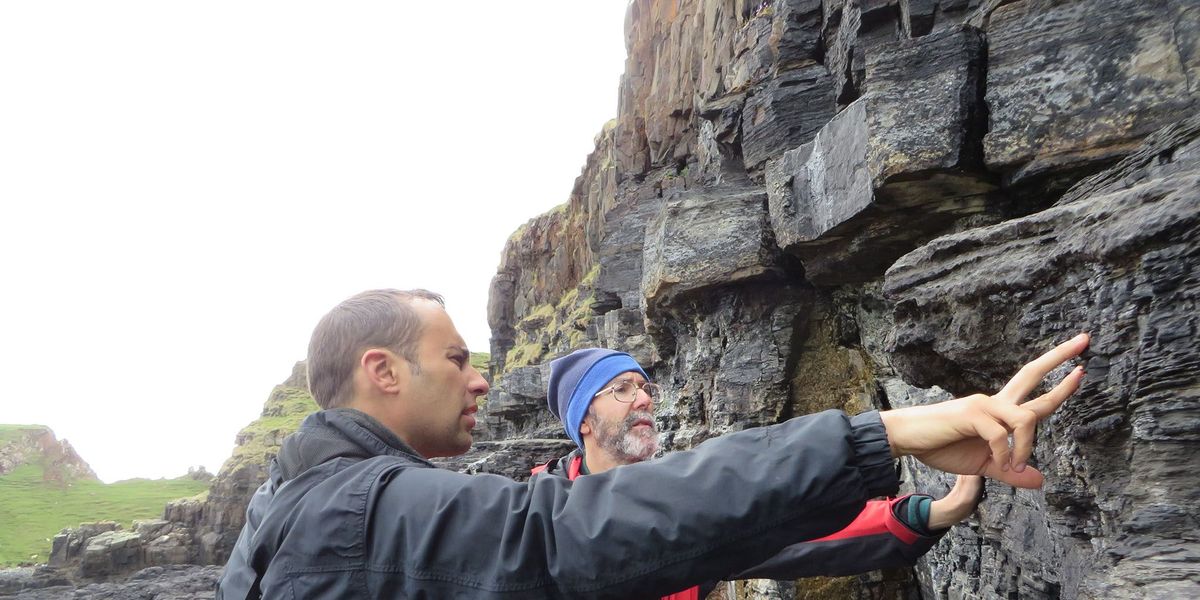 Steve Brusatte links en Mark Wilkinson onderzoeken de klif waarlangs de route met de dinosaurirsporen loopt