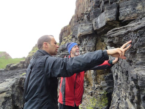 Steve Brusatte links en Mark Wilkinson onderzoeken de klif waarlangs de route met de dinosaurirsporen loopt