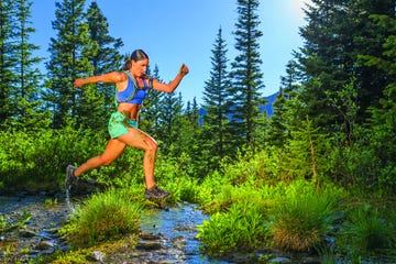 hispanic woman jumping over stream