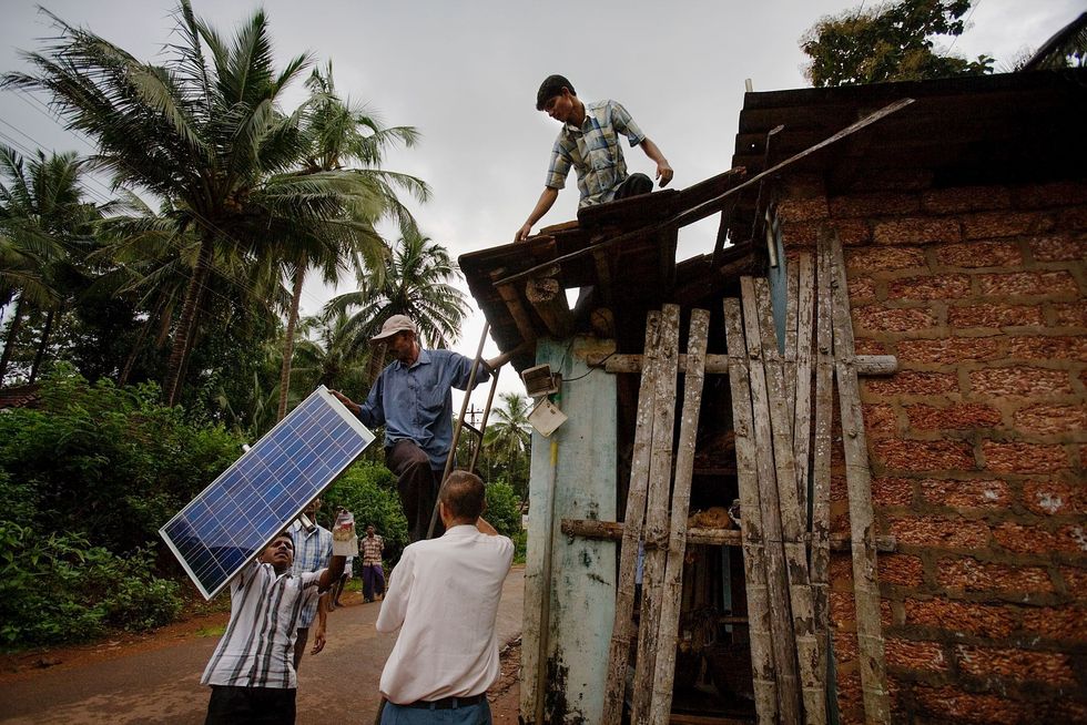 Op het dak van een kleine kruidenierswinkel in het Indiase dorp Sulya Taluk wordt een zonnepaneel van bijna 430 euro genstalleerd De eigenaar hoopt de kosten terug te verdienen doordat hij kan besparen op kerosine