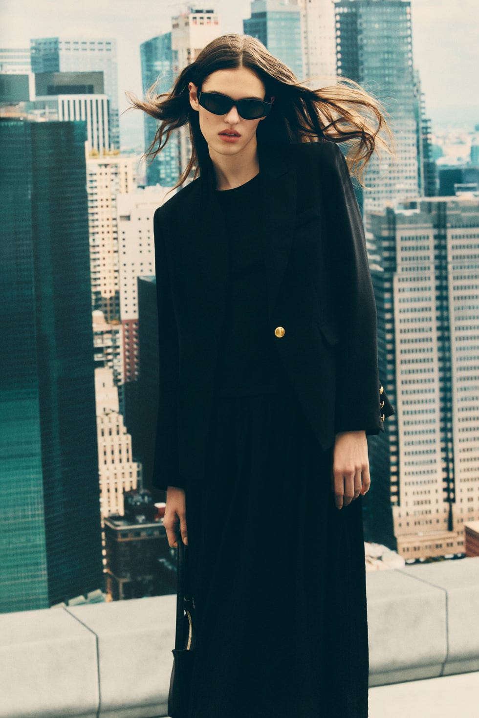 model wearing a black outfit with urban skyline in the background