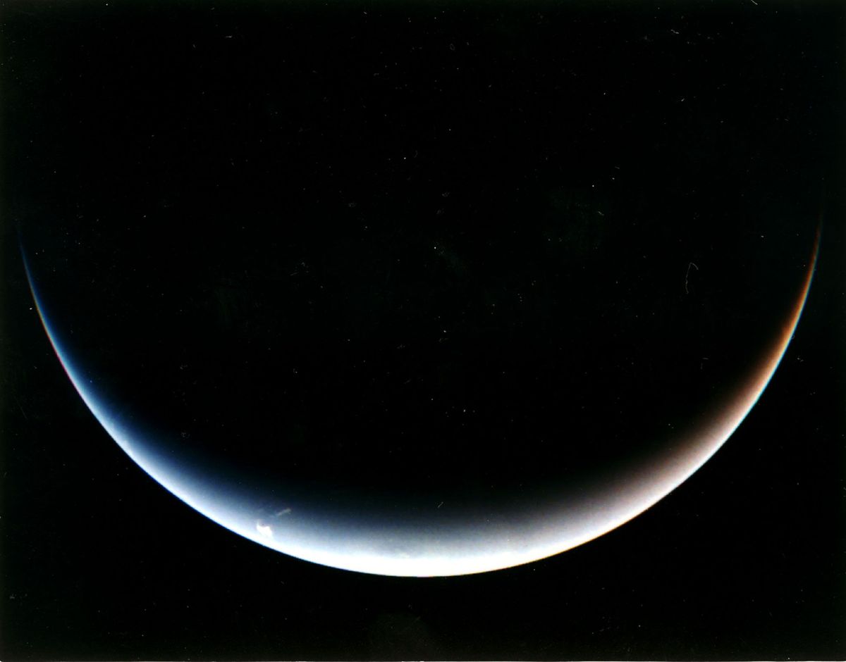 Neptunus ziet eruit als een pastelkleurige sikkel op deze foto van Voyager 2 die werd genomen toen de ruimtesonde wegvloog van de planeet op weg naar de verre ruimte