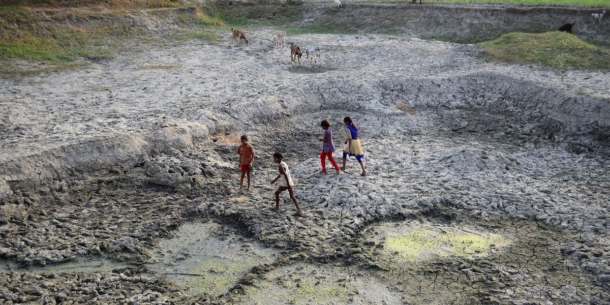 Indiase kinderen spelen op een uitgedroogd stuk grond in de bedding van de geslonken Varuna een zijrivier van de Ganges