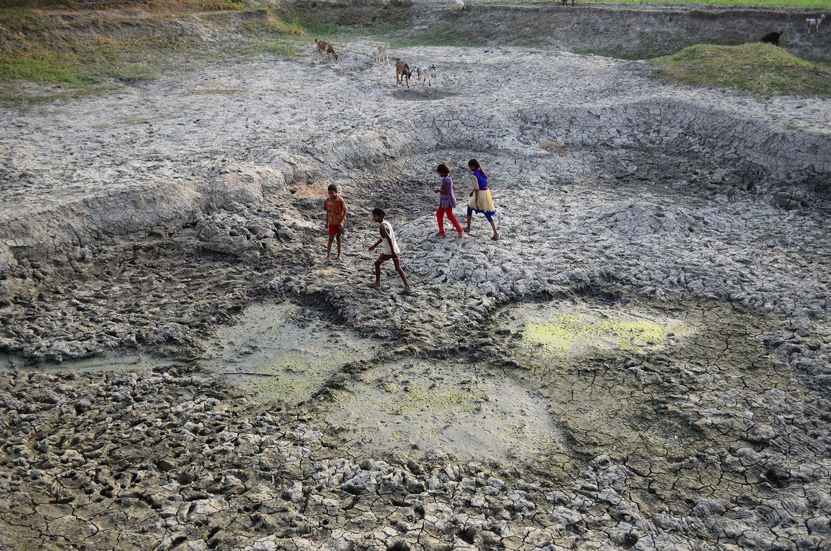 Indiase kinderen spelen op een uitgedroogd stuk grond in de bedding van de geslonken Varuna een zijrivier van de Ganges