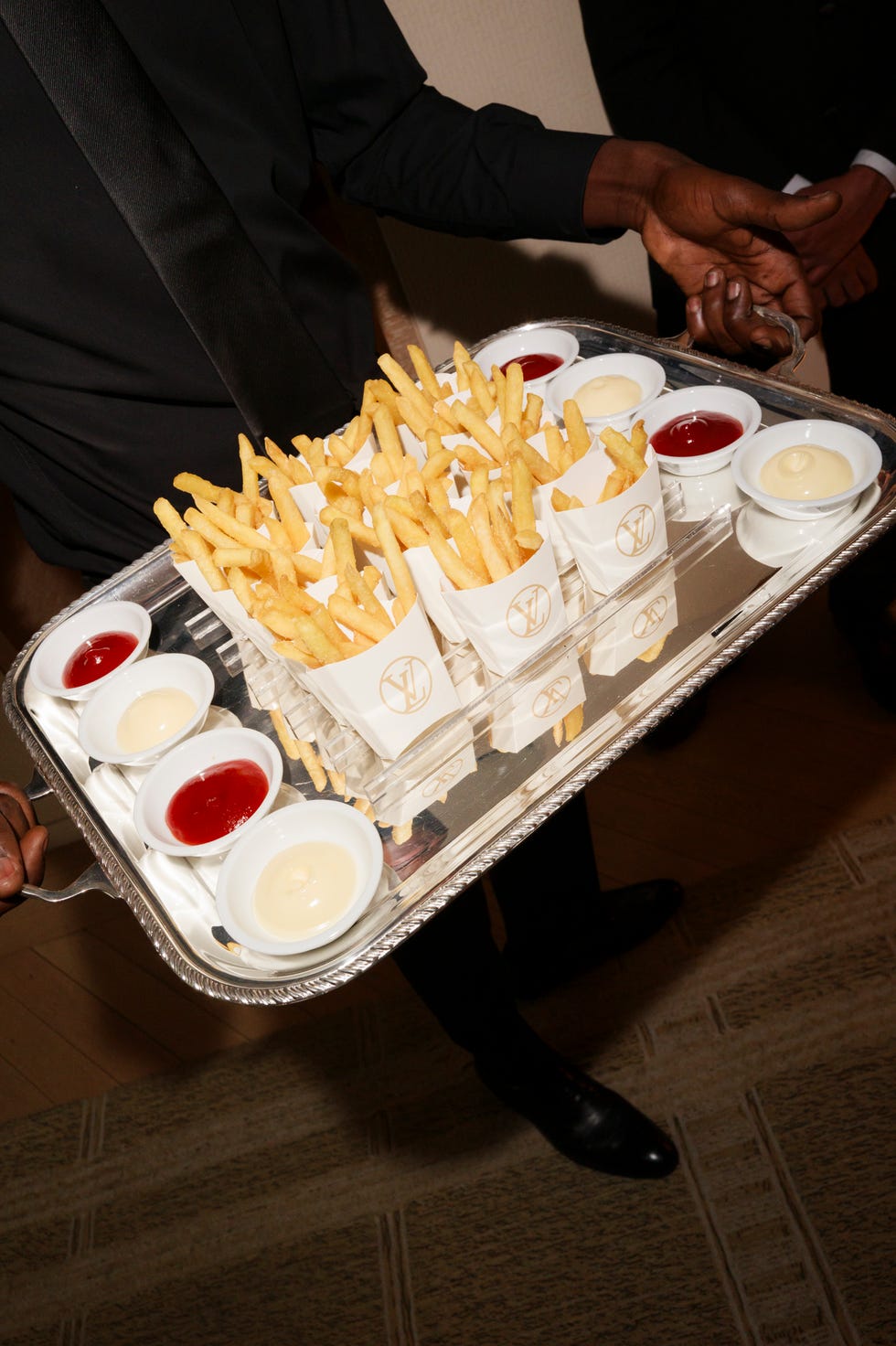 a silver tray holding french fries and dipping sauces