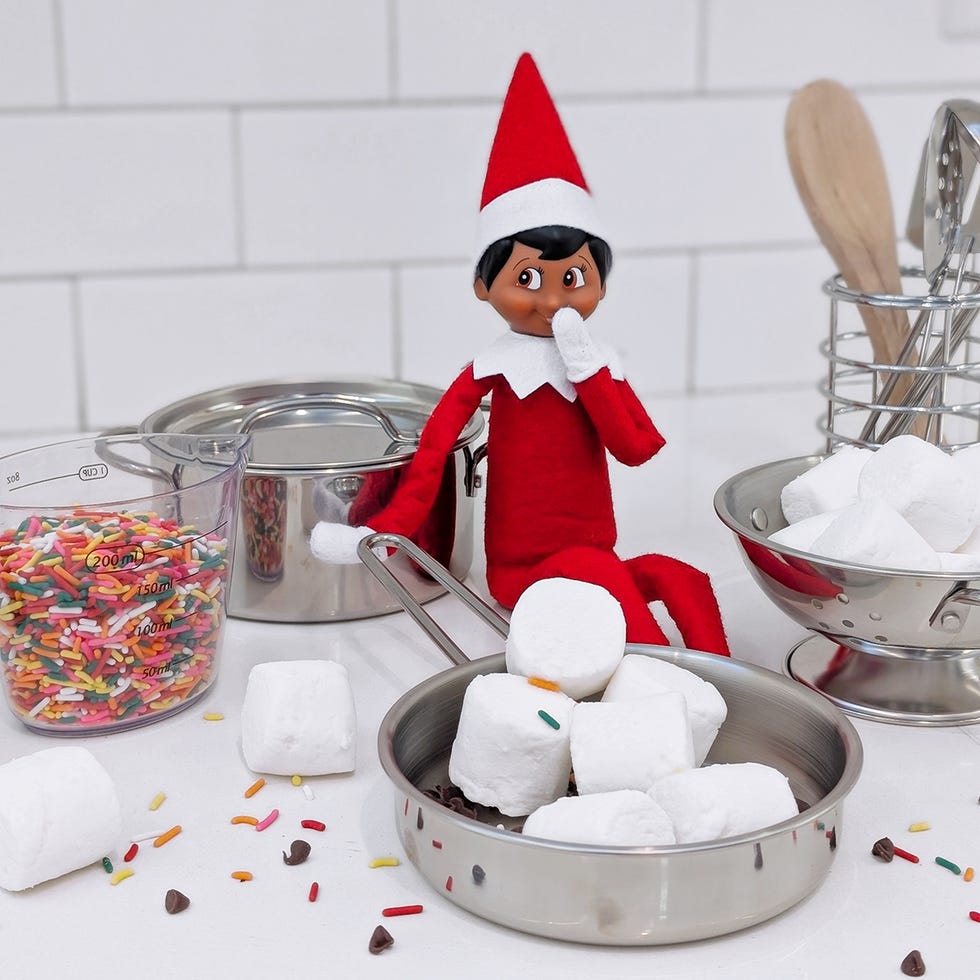 an elf has a small pan filled with marshmallows, sprinkles and chocolate chips