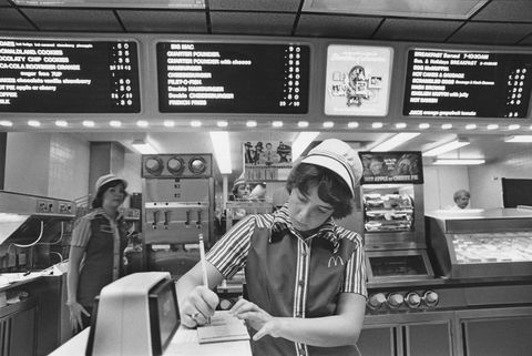an employee wearing the mcdonald’s uniform with stripes and a white hat takes down an order in 1978, long before automated technology