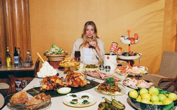 a lavish spread of food assembled on a table with drinks and a person holding a glass