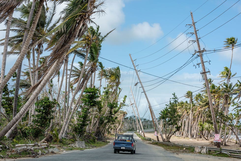 Vijf maanden na de storm buigen elektriciteitspalen en palmbomen gevaarlijk door boven een uitvalsweg ten noorden van Punta Santiago Extreme windstoten en een zware stormvloed richtten grote schade in het stadje aan