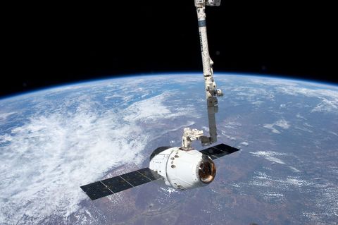 Ruimtevaartuig Dragon komt op 25 mei 2012 aan bij het Internationaal ruimtestation ISS terwijl op de achtergrond de aarde te zien is De Dragon had voorraden voor het ISS en de bemanning aan boord Het was het eerste commercile ruimtevaartuig dat naar het ruimtestation ging Op 31 mei werd de Dragon succesvol van het station afgekoppeld en keerde terug naar aarde