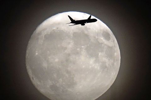 A commerical jet flies in front of the November 2016 supermoon on its approach to Heathrow Airport in London