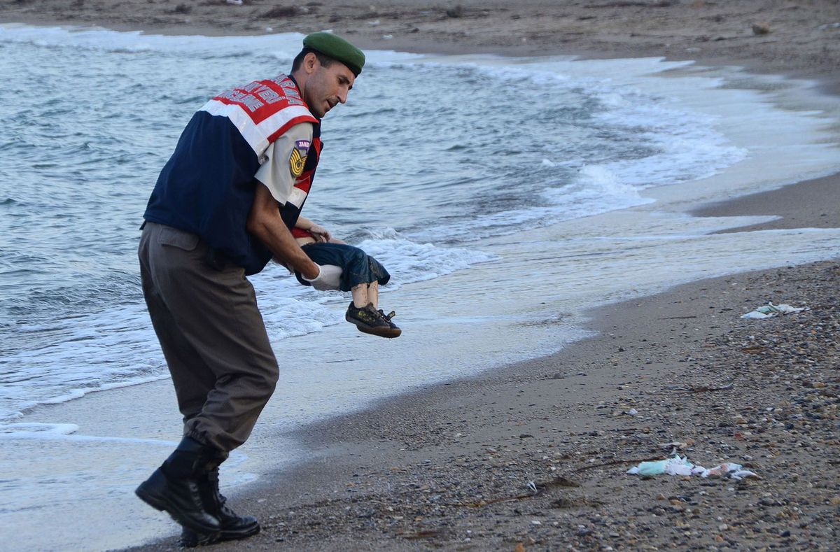 Een Turkse politieman draagt het lichaam van de driejarige Aylan Kurdi voorzichtig nadat hij woensdag aanspoelde Hij zat op de boot met Syrische vluchtelingen die zonk in een poging het Griekse eiland  te bereiken