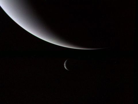 Neptunus maan Triton lijkt onder de ijsreus te hangen in dit beeld van Voyager 2