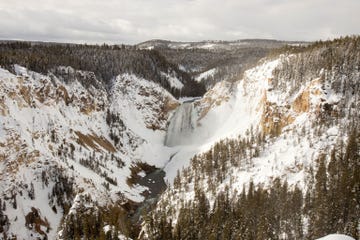 De Lower Falls in de winter gezien vanaf de overkant van de rivier Yellowstone in Yellowstone National Park in de staat Wyoming Doordat er veel regen viel op de sneeuw in het park ontstonden er overstromingen waarbij wegen en bruggen in en rond het park verdwenen
