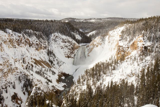 De Lower Falls in de winter gezien vanaf de overkant van de rivier Yellowstone in Yellowstone National Park in de staat Wyoming Doordat er veel regen viel op de sneeuw in het park ontstonden er overstromingen waarbij wegen en bruggen in en rond het park verdwenen