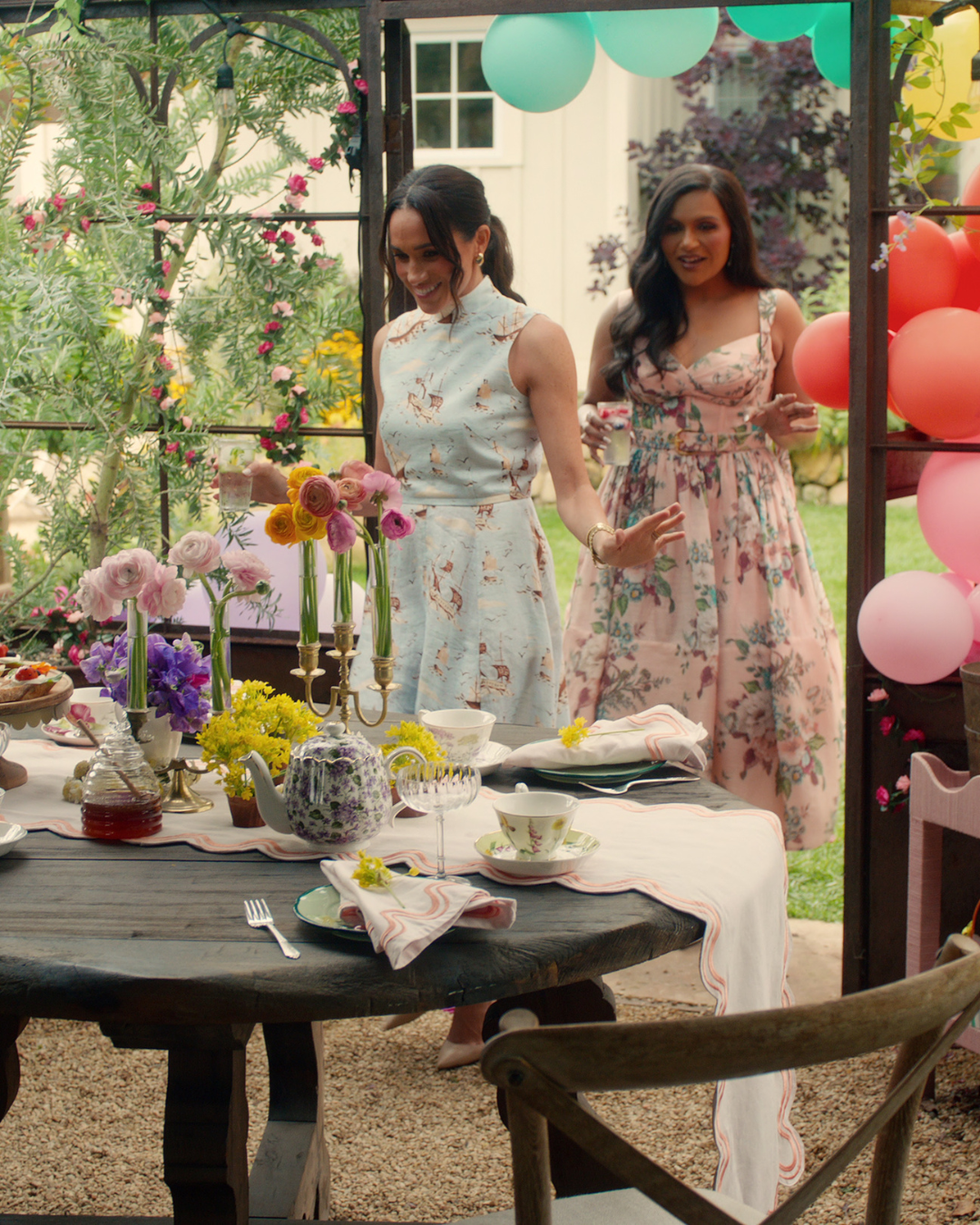 Social gathering setup with floral decorations, food, and drinks on a table.