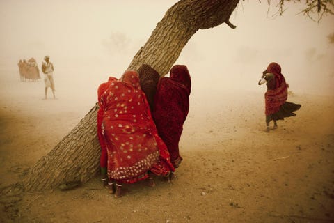 Op deze National Geographicfoto uit 1984 beschermen vrouwen zich tegen de stevige wind die vooraf gaat aan de moesson in Rajasthan in India