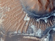 De bodem van de afgesleten inslagkrater Aram Chaos ten oosten van het canyonstelsel Valles Marineris is bezaaid met duinen Ontsloten gesteenten te herkennen aan de verschillend gekleurde stroken aan de onderzijde van de foto kunnen ijzerhoudende sulfaten en kleimineralen bevatten die op de aanwezigheid van water in het verleden wijzen
