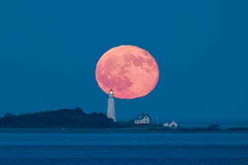 De volle maan komt op 10 juli 2017 op boven de vuurtoren Boston Light Het oorspronkelijke lichtbaken  dat op Little Brewster Island staat zon vijftien kilometer uit de kust bij Boston  werd in 1716 gebouwd en was de allereerste vuurtoren in de VS