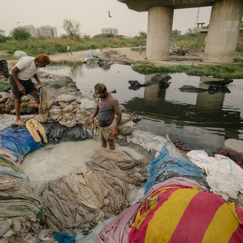 Mannen bleken wasgoed voordat ze het in de vervuilde rivier de Jamuna uitspoelen