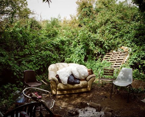 Een bewoner slaapt op een bank in Grow Heathrow Bezoekers komen naar het ecodorp om meer te weten te komen over het werk van de bewoners aan workshops en kunstprojecten deel te nemen en maandelijkse open micoptredens bij te wonen