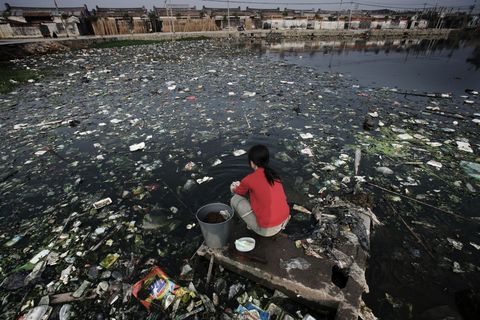 Een vrouw zit op een vlonder in een van de ernstig vervuilde rivieren en meren in de provincie Guangdong