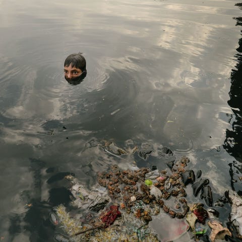 Ook kinderen verzamelen afval voor recycling zoals hier in de rivier de Jamuna waar ze zoeken naar religieuze voorwerpen die vanaf bruggen in het water zijn gegooid De spullen van muntjes tot metalen beeldjes kunnen worden verkocht aan recyclingbedrijfjes