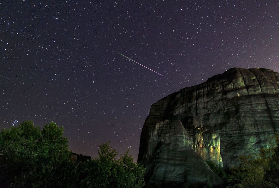 Boven de plaats Meteora een Werelderfgoed in Griekenland schiet een stralende Persedenmeteoor door de nachthemel