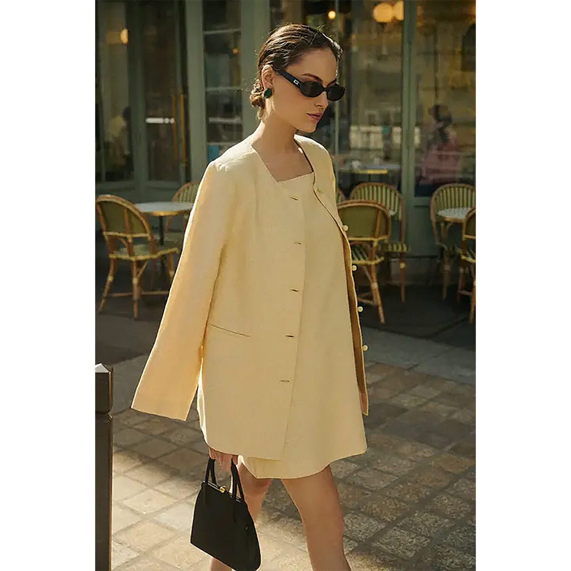 a woman in a yellow outfit walking past outdoor café seating