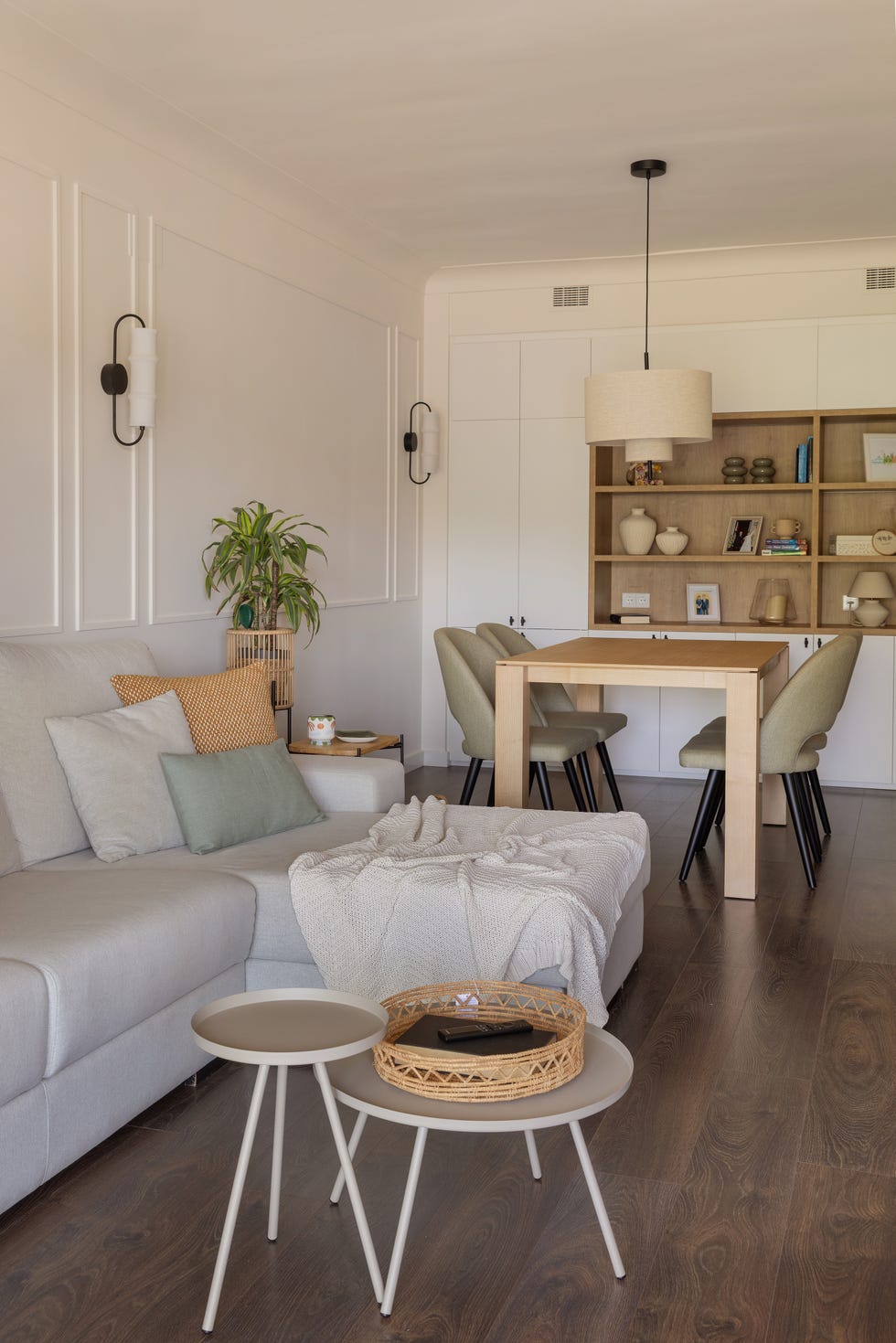 salón comedor con sofá con chaiselongue gris y molduras blancas en la pared