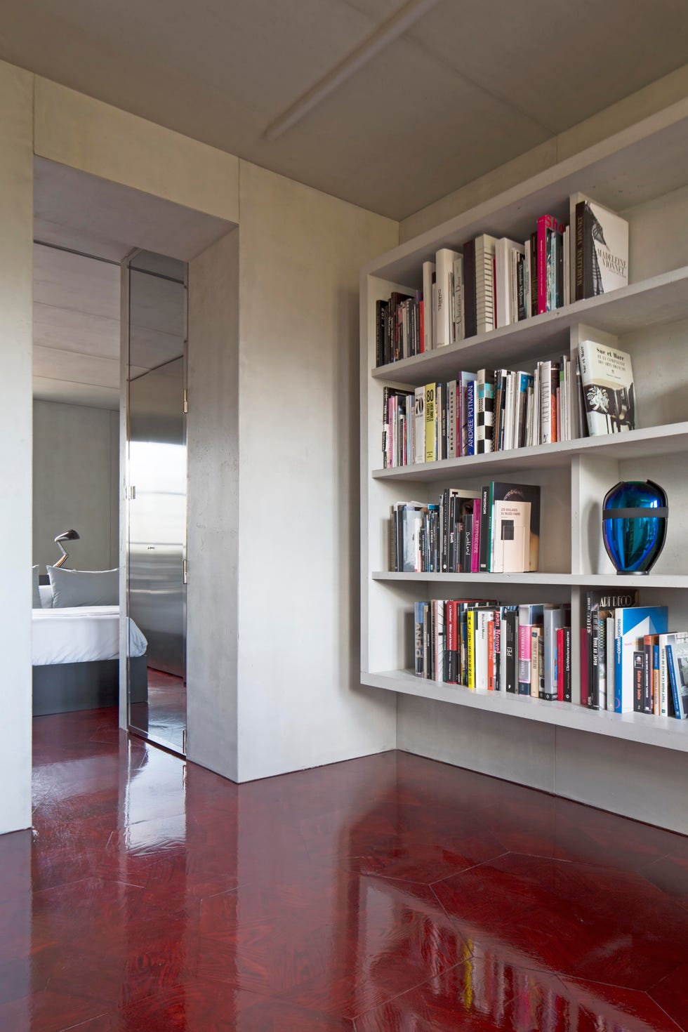 view of living area in apartment with glossy red floor and bookshelf