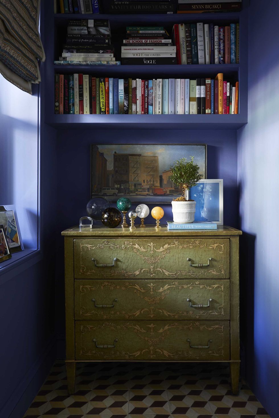 blue painted walls, green dresser, marble balls, decorative books, white potted plant