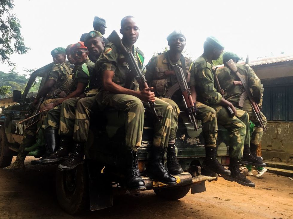 Congolese soldaten en parkopzichters van het Okapiwildpark begeleiden de lichamen van de mensen die door rebellen werden gedood toen ze een stilgelegde goudmijn bewaakten