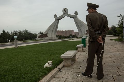 Een soldaat met hond bij een standbeeld dat oproept tot de hereniging van het Koreaanse schiereiland