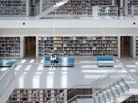 Via dakramen valt zonlicht op iemand die in de Stadtbibliothek Stuttgart in Duitsland zit te lezen Van buiten is de bibliotheek een grote kubus die er overdag wit uitziet maar die kleur gaat s avonds over in oplichtend koningsblauw