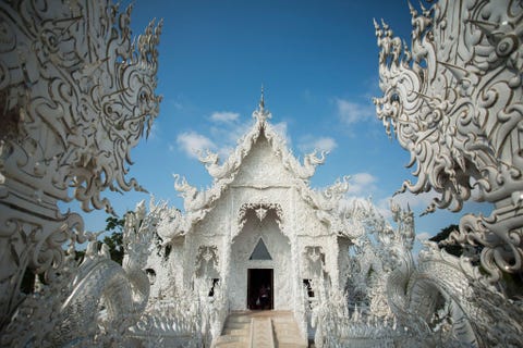 Wat Rong Khun ThailandDe compleet witte Wat Rong Khuntempel in NoordThailand is in 1997 gesticht De tempel is door de Thaise schilder Chalermchai Kositpipat ontworpen en gefinancierd De buitenkant is bekleed met een mozaek van spiegeltjes Afbeeldingen van Spider Man Michael Jackson en Hello Kitty fleuren het kleurrijke interieur van de hoofdtempel op Ondanks de contemporaine uitstraling wordt van bezoekers verwacht dat ze zich volgens traditionele wijze kleden en gedragen