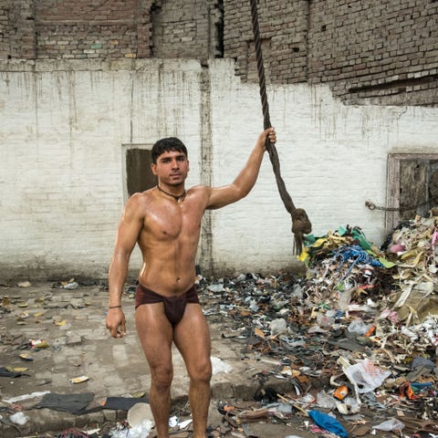 Een pehlwanbereidt zich voor op de training door in een boom te klimmen Deze trainingsplaats in de buurt van de soefischrijn in het ommuurde centrum van Lahore ligt naast een recyclingvoorziening